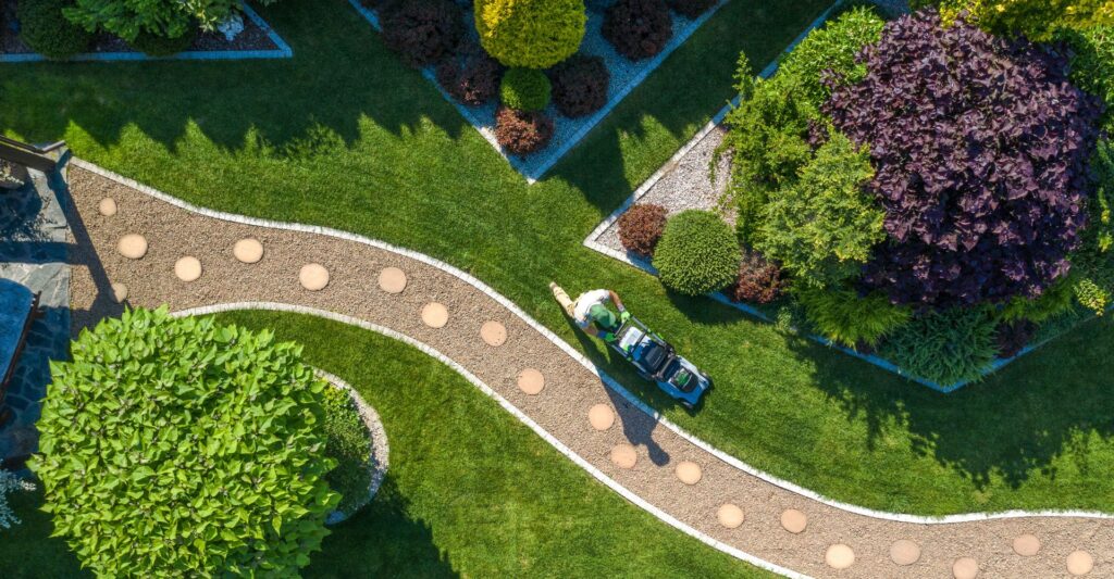 A landscaper mowing beside a beautiful stone pathway in a yard
